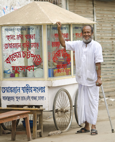 Abdul Kashem, a client with physical disability, beside his food cart