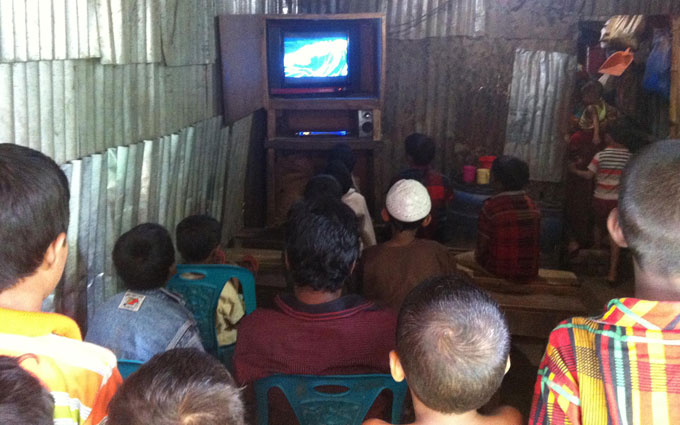 Children of all ages watch Doraemon together in the tin-shed clubhouse set up by a microfiance client.