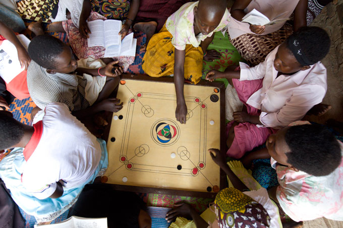 Members of an ELA club in Uganda gather around to play carom board, a popular indoor game.